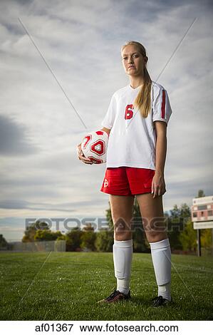 Low angle portrait of athlete standing with soccer ball on field under cloudy sky View Large Photo Image Stock Photo - Low angle portrait of athlete standing with soccer ball on field under cloudy sky. Fotosearch