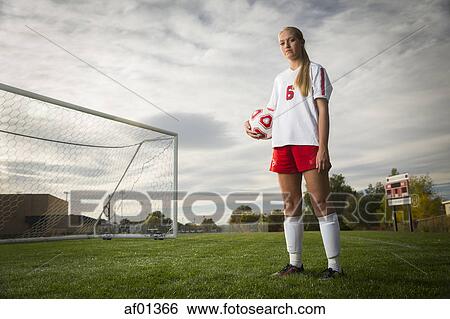 Low angle portrait of athlete standing with soccer ball on field under cloudy sky View Large Photo Image Stock Photograph - Low angle portrait of athlete standing with soccer ball on field under cloudy sky. Fotosearch