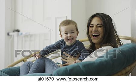 Low angle selective focus portrait of mother and baby son posing and sitting in chair View Large Photo Image Stock Image - Low angle selective focus portrait of mother and baby son posing and sitting in chair. Fotosearch