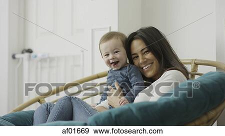 Low angle selective focus portrait of mother and baby son posing and sitting in chair View Large Photo Image Stock Photo - Low angle selective focus portrait of mother and baby son posing and sitting in chair. Fotosearch