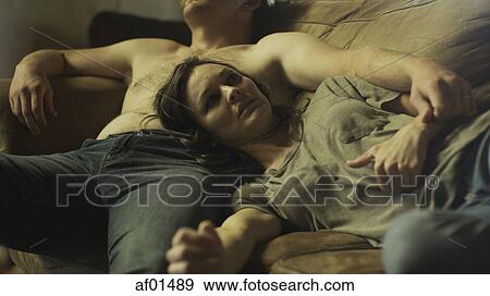 Low angle selective focus view of dazed girlfriend laying on boyfriend on dingy sofa View Large Photo Image Stock Photo - Low angle selective focus view of dazed girlfriend laying on boyfriend on dingy sofa. Fotosearch