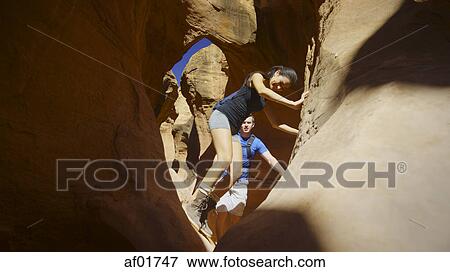 Low angle selective focus view of boyfriend and girlfriend exploring cave in scenic rock formations View Large Photo Image Stock Photo - Low angle selective focus view of boyfriend and girlfriend exploring cave in scenic rock formations. Fotosearch