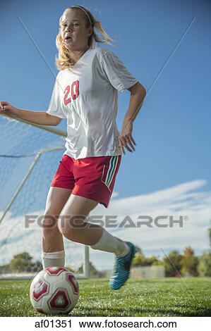 Low angle view of athlete kicking soccer ball on field under blue sky on sunny day View Large Photo Image Stock Image - Low angle view of athlete kicking soccer ball on field under blue sky on sunny day. Fotosearch