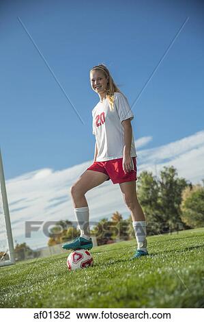 Low angle view of athlete standing with soccer ball on field under blue sky on sunny day View Large Photo Image Stock Image - Low angle view of athlete standing with soccer ball on field under blue sky on sunny day. Fotosearch
