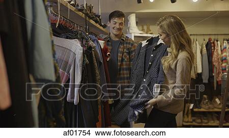 Low angle view of boyfriend and girlfriend admiring clothing in fashion store View Large Photo Image Picture - Low angle view of boyfriend and girlfriend admiring clothing in fashion store. Fotosearch