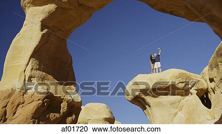 Low angle view of boyfriend and girlfriend taking selfie with smartphone on scenic rock formations under clear blue sky View Large Photo Image Stock Image - Low angle view of boyfriend and girlfriend taking selfie with smartphone on scenic rock formations under clear blue sky. Fotosearch