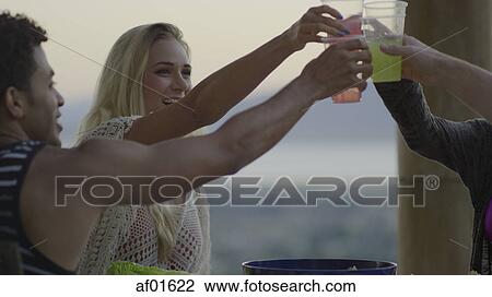 Low angle view of friends toasting outdoors with drinks View Large Photo Image Stock Image - Low angle view of friends toasting outdoors with drinks. Fotosearch