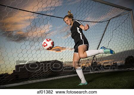 Low angle view of goalie kicking soccer ball in goal under blue sky View Large Photo Image Stock Image - Low angle view of goalie kicking soccer ball in goal under blue sky. Fotosearch
