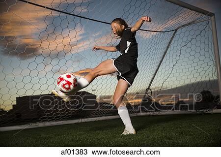 Low angle view of goalie kicking soccer ball in goal under blue sky View Large Photo Image Stock Image - Low angle view of goalie kicking soccer ball in goal under blue sky. Fotosearch