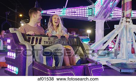 Low angle view of happy laughing couple sitting on amusement park funfair ride View Large Photo Image Stock Photo - Low angle view of happy laughing couple sitting on amusement park funfair ride. Fotosearch