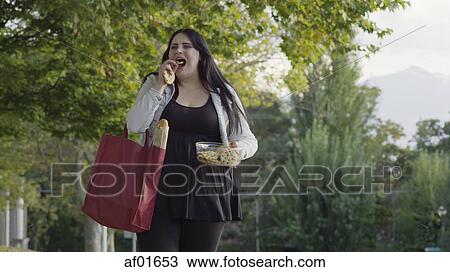 Low angle view of happy woman walking and eating groceries View Large Photo Image Stock Image - Low angle view of happy woman walking and eating groceries. Fotosearch