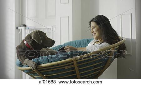 Low angle view of pet dog and woman using smartphone and sitting in chair View Large Photo Image Stock Photo - Low angle view of pet dog and woman using smartphone and sitting in chair. Fotosearch