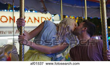Low angle view of romantic boyfriend and girlfriend kissing on carousel at amusement park funfair View Large Photo Image Stock Photo - Low angle view of romantic boyfriend and girlfriend kissing on carousel at amusement park funfair. Fotosearch