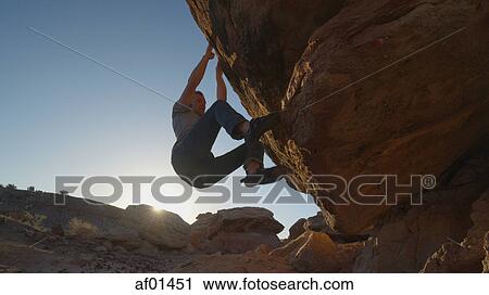 Low angle view of silhouette of climber clinging to steep rock cliff under blue sky View Large Photo Image Stock Image - Low angle view of silhouette of climber clinging to steep rock cliff under blue sky. Fotosearch