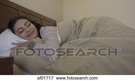 Low angle view of smiling woman laying in comfortable bed blankets View Large Photo Image Stock Photo - Low angle view of smiling woman laying in comfortable bed blankets. Fotosearch