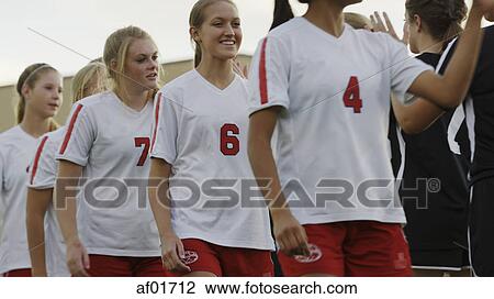 Stock Image - Low angle view of soccer athletes saluting opposition team outdoors in game. Fotosearch