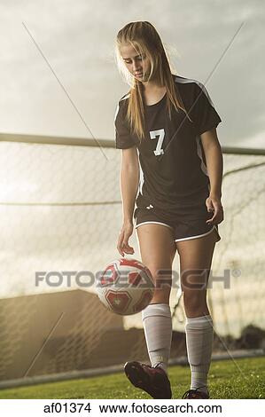 Low angle view of soccer player kicking ball on field under sunset sky View Large Photo Image Picture - Low angle view of soccer player kicking ball on field under sunset sky. Fotosearch