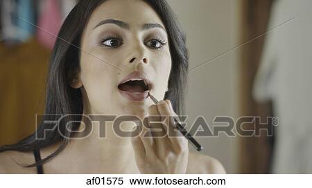 Low angle view of woman applying lipstick makeup in mirror View Large Photo Image Stock Photography - Low angle view of woman applying lipstick makeup in mirror. Fotosearch
