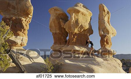 Low angle view of woman dancing and posing on rock formations in remote desert landscape under clear blue sky View Large Photo Image Stock Photography - Low angle view of woman dancing and posing on rock formations in remote desert landscape under clear blue sky. Fotosearch