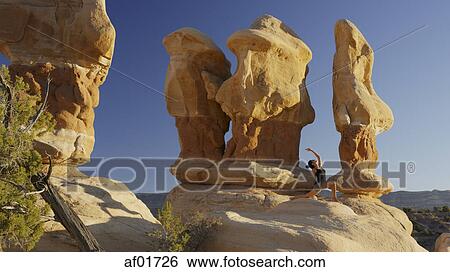 Low angle view of woman practicing yoga and meditating on rock formations in remote desert landscape under clear blue sky View Large Photo Image Stock Photograph - Low angle view of woman practicing yoga and meditating on rock formations in remote desert landscape under clear blue sky. Fotosearch