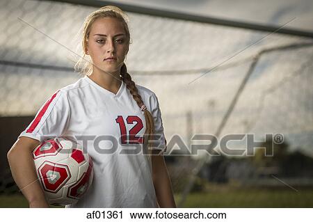 Low angle waist up portrait of serious athlete standing and holding ball in soccer goal View Large Photo Image Stock Image - Low angle waist up portrait of serious athlete standing and holding ball in soccer goal. Fotosearch