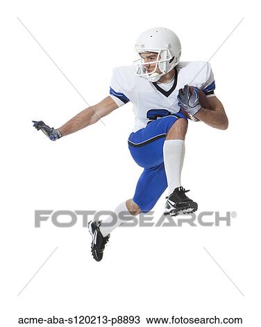 Stock Image - Male player of American football running with ball, studio shot. Fotosearch