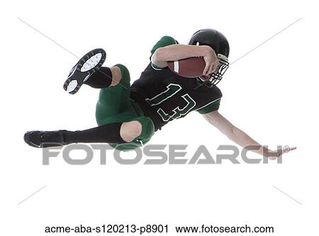 Stock Image - Male player of American football catching ball, studio shot. Fotosearch