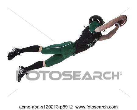 Stock Image - Male player of American football catching ball, studio shot. Fotosearch