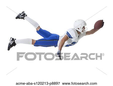 Stock Photo - Male player of American football catching ball, studio shot. Fotosearch