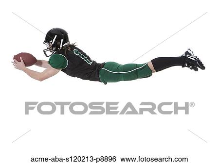 Stock Photograph - Male player of American football catching ball, studio shot. Fotosearch