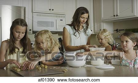 Stock Image - Mother and daughters baking cookies together in kitchen. Fotosearch