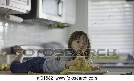 Naughty messy girl laying on kitchen counter eating plate of spaghetti View Large Photo Image Stock Image - Naughty messy girl laying on kitchen counter eating plate of spaghetti. Fotosearch