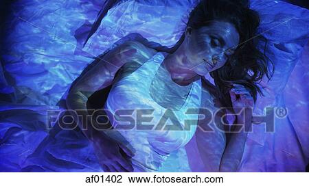 Stock Image - Ocean projection on sleeping woman laying in bed. Fotosearch