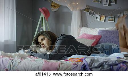 Pensive teenage girl laying on bed View Large Photo Image Stock Photography - Pensive teenage girl laying on bed. Fotosearch