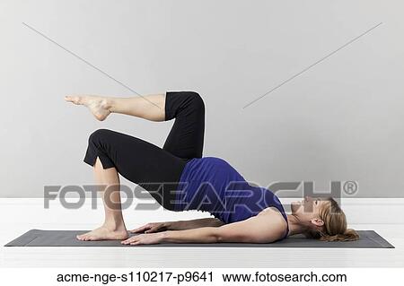 Stock Image - Portrait of pregnant woman exercising, studio shot. Fotosearch