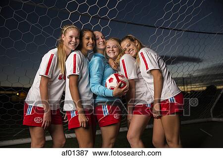 Portrait of smiling soccer team hugging in goal under sunset sky View Large Photo Image Stock Photo - Portrait of smiling soccer team hugging in goal under sunset sky. Fotosearch