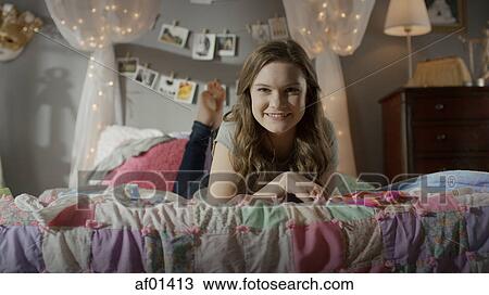 Portrait of smiling teenage girl laying on bed View Large Photo Image Stock Image - Portrait of smiling teenage girl laying on bed. Fotosearch
