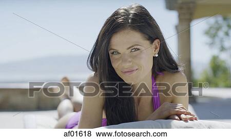 Portrait of smiling woman in bikini sunbathing on lawn chair near pool View Large Photo Image Stock Photo - Portrait of smiling woman in bikini sunbathing on lawn chair near pool. Fotosearch