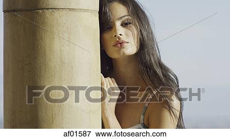 Portrait of sultry woman with long hair standing behind pole View Large Photo Image Stock Photo - Portrait of sultry woman with long hair standing behind pole. Fotosearch