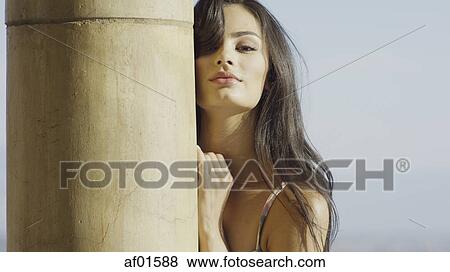 Portrait of sultry woman with long hair standing behind pole View Large Photo Image Stock Photo - Portrait of sultry woman with long hair standing behind pole. Fotosearch