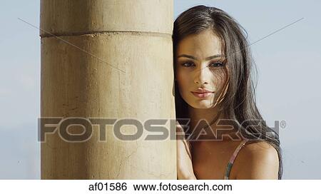 Portrait of sultry woman with long hair standing behind pole View Large Photo Image Stock Photograph - Portrait of sultry woman with long hair standing behind pole. Fotosearch