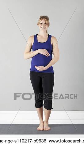 Stock Photograph - Portrait of young pregnant woman in sports clothing, studio shot. Fotosearch