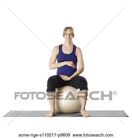 Stock Photo - Portrait of young pregnant woman sitting on fitness ball, studio shot. Fotosearch