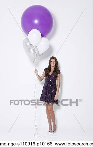 Stock Photograph - Portrait of young woman holding balloons at party. Fotosearch