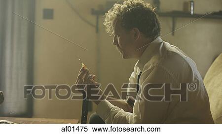 Stock Photography - Profile of drug addict loading syringe needle for injection. Fotosearch