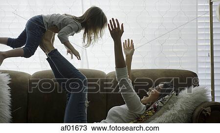 Profile of laughing playful mother lifting daughter in mid-air and playing on sofa View Large Photo Image Stock Image - Profile of laughing playful mother lifting daughter in mid-air and playing on sofa. Fotosearch