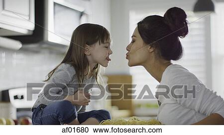 Profile of playful mother and daughter kissing over spaghetti pasta in kitchen View Large Photo Image Stock Image - Profile of playful mother and daughter kissing over spaghetti pasta in kitchen. Fotosearch
