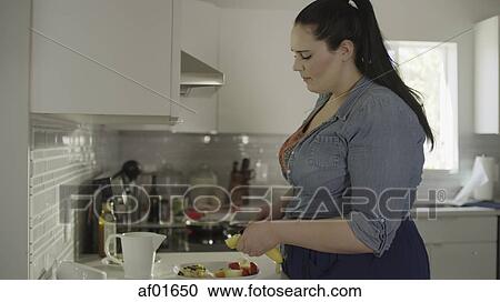Profile of serious woman standing chopping fruit in kitchen View Large Photo Image Stock Image - Profile of serious woman standing chopping fruit in kitchen. Fotosearch