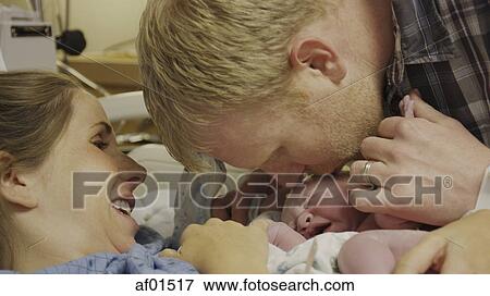 Profile view of new mother and father admiring newborn baby in hospital View Large Photo Image Stock Photo - Profile view of new mother and father admiring newborn baby in hospital. Fotosearch