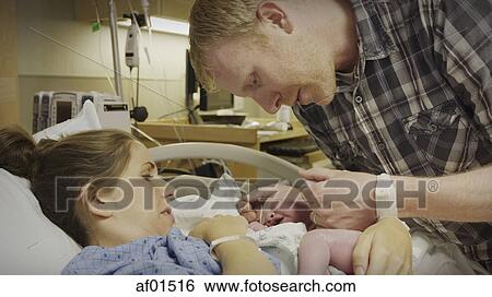 Profile view of new mother and father admiring newborn baby in hospital View Large Photo Image Stock Photograph - Profile view of new mother and father admiring newborn baby in hospital. Fotosearch